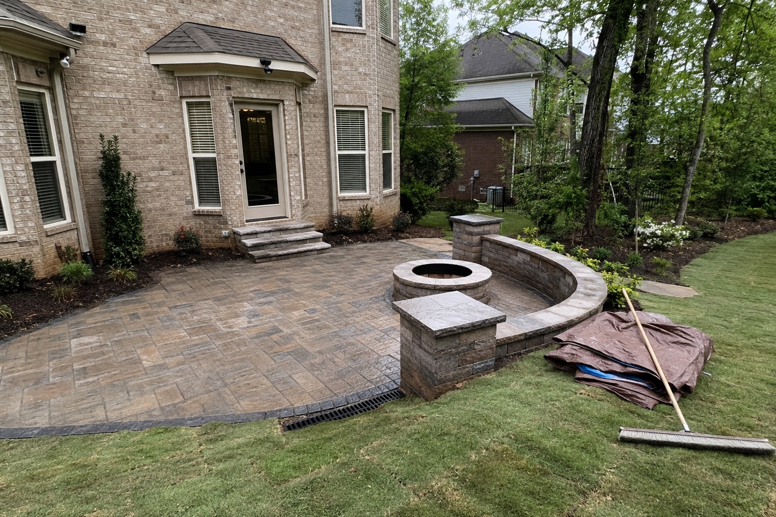 Backyard paver patio with a fire pit and seat wall
